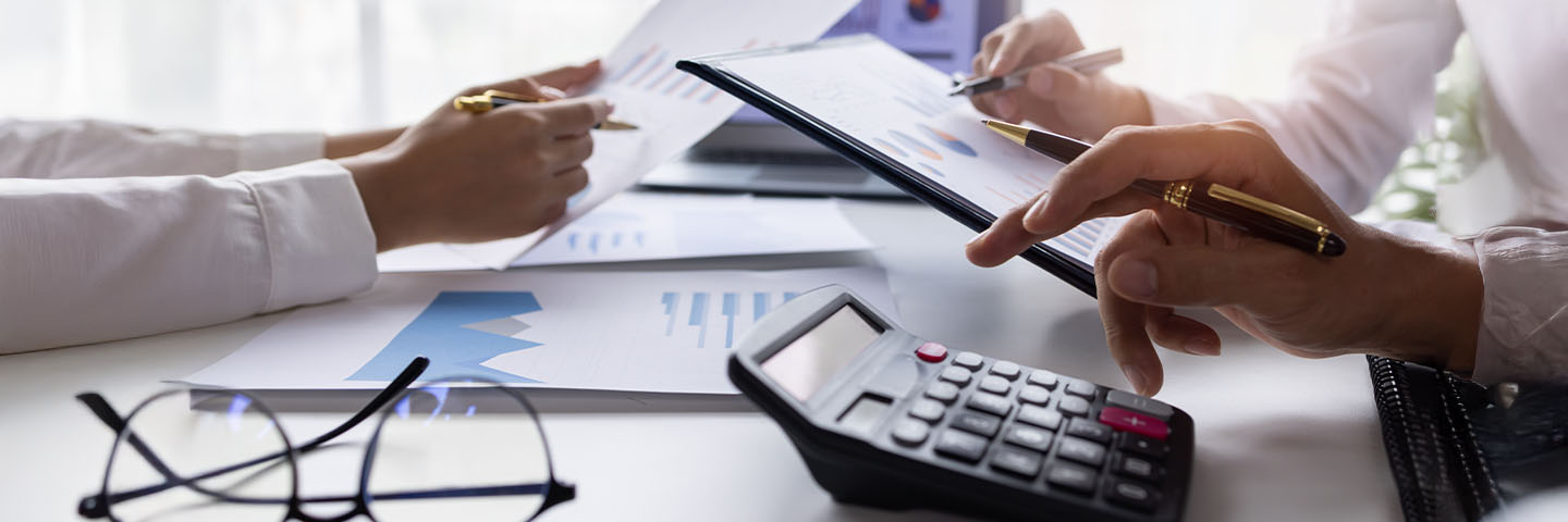 Two people using a calculator and studying documents