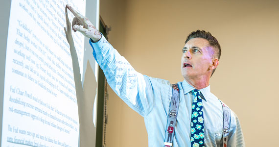 Professor pointing to a whiteboard.