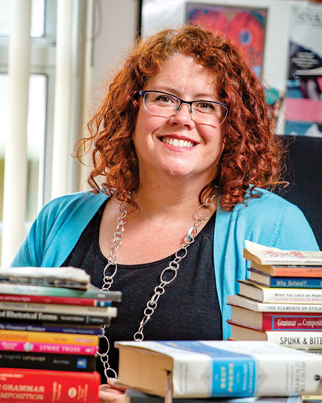 Dr. Katherine Cottle, sitting at a table with stacks of books