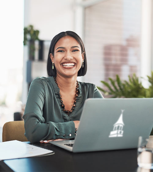 WilmU employee smiling at computer.